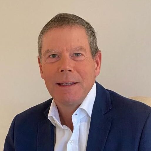 Photo of a man in a blue suite sitting on a chair.