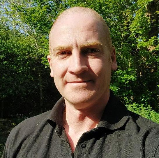 Headshot of a man standing in front of a tree