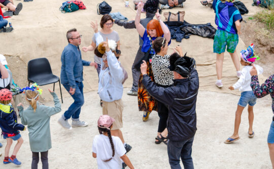 A diverse group of people dance on a chalk circle.