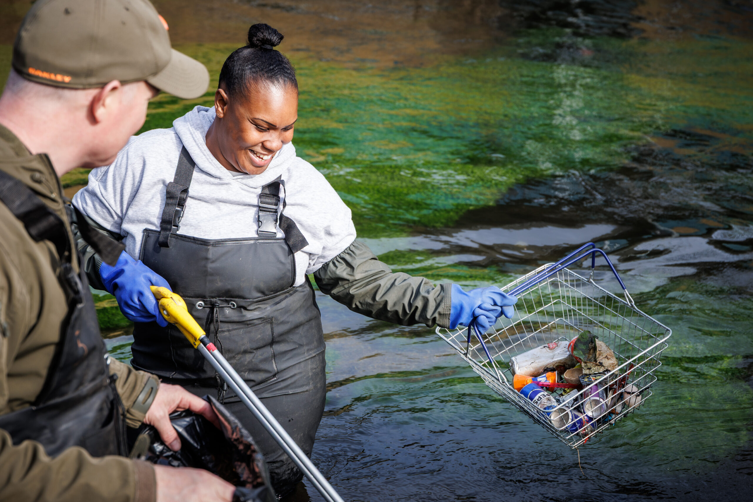 young woman taking part in a river clean and collecting litter