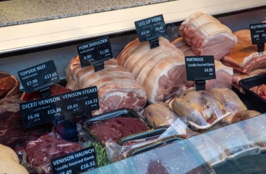 A butcher's counter with different cuts of meat, one labelled as venison.