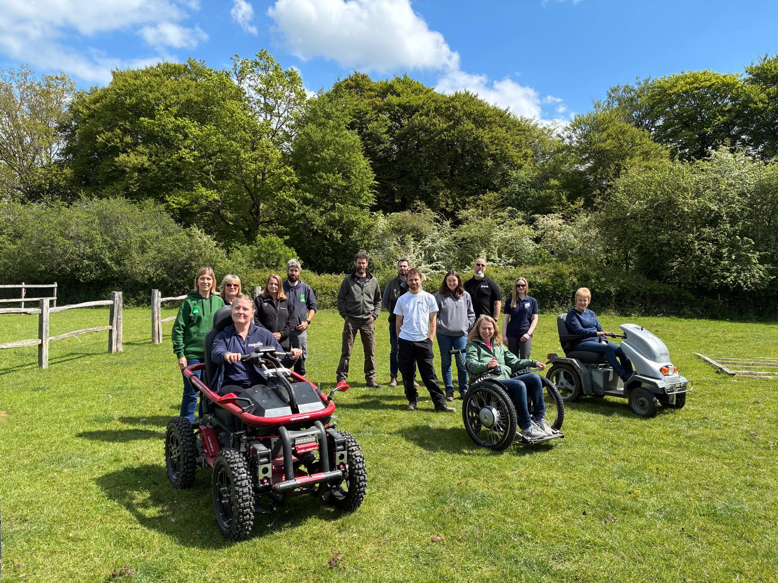 People using all-terrain mobility equipment in a green field with blue sky