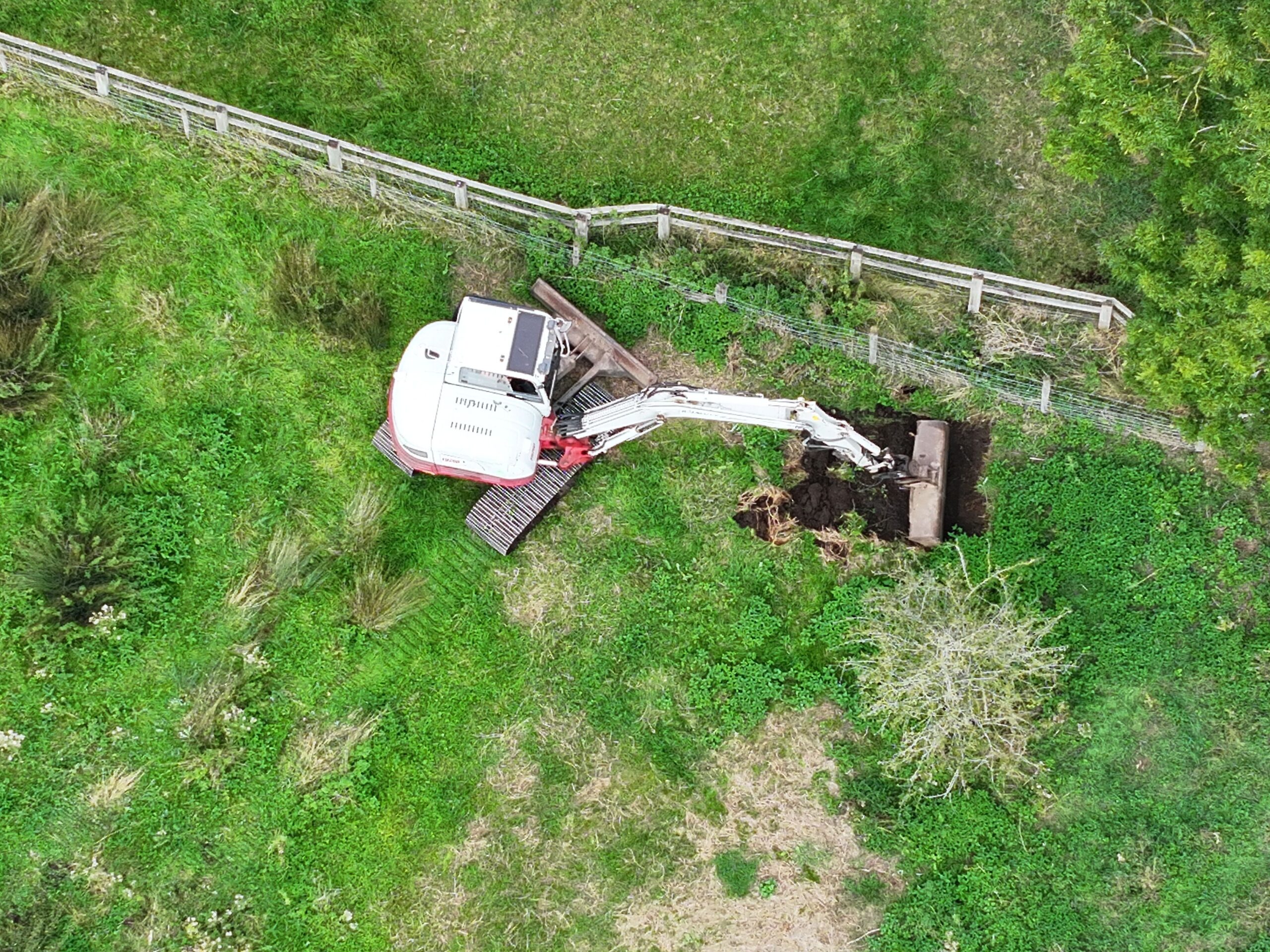 Aerial photo of a digger in a green field removing top soil