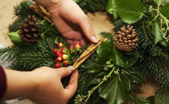 hands adding foliage to a Christmas wreath